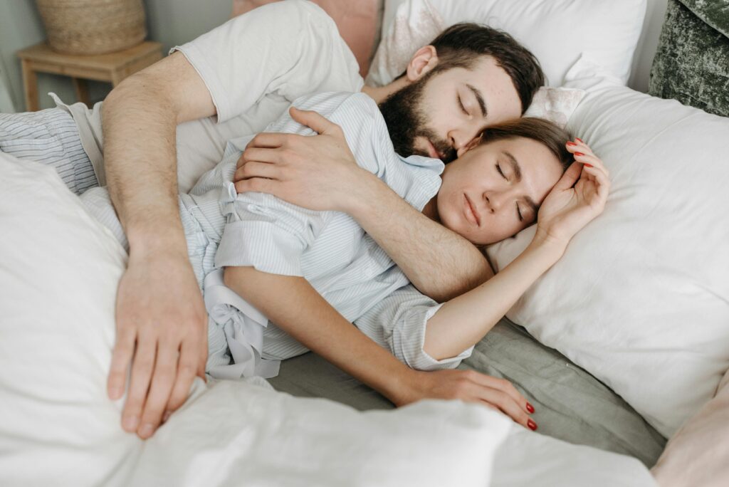 Man and woman snuggling together in bed, peacefully enjoying a deep, restful sleep.