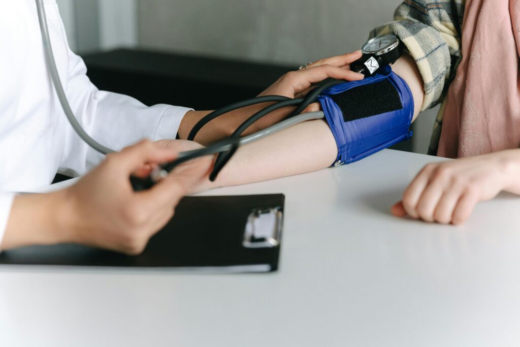 Doctor checking a person's blood pressure with a cuff and monitor during a medical examination.